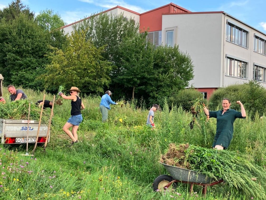 Schülerinnen, Schüler und Lehrkräfte bei der Arbeit auf dem Schulacker vor dem Neubau