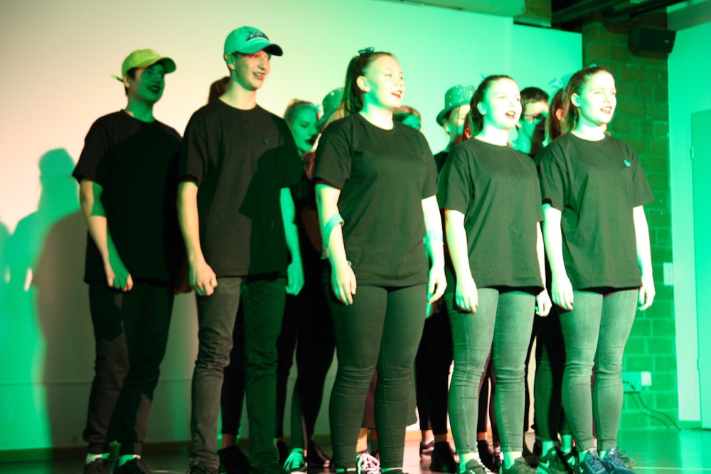 Schülerinnen und Schüler singen gemeinsam auf der Bühne der Präsentationsshow